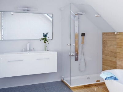 Eckdusche mit einer Tür unter Schräge neben Waschbecken im Bad